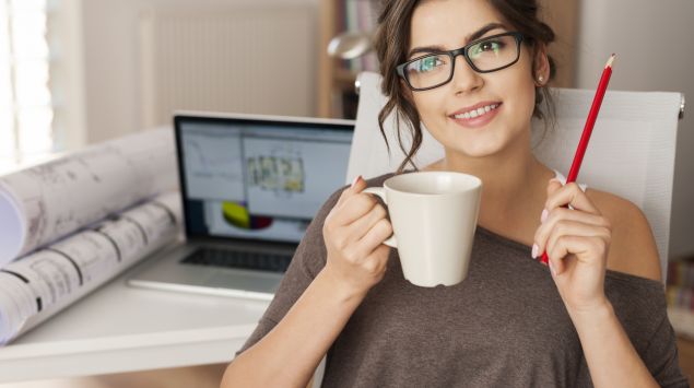 Eine Frau sitzt neben Ihrem Laptop und überlegt.