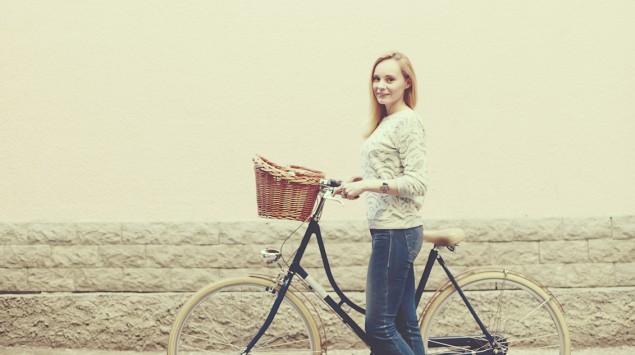 Eine Frau steht mit ihrem Fahrrad auf der Straße.