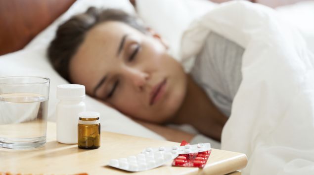 Eine Frau liegt krank im Bett und schläft.