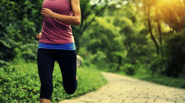 Eine Frau joggt durch einen Park.