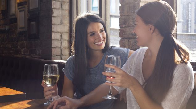 Zwei Frauen trinken zusammen ein Glas Wein.