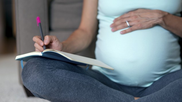 Schwangere schreibt in ein Notzibuch