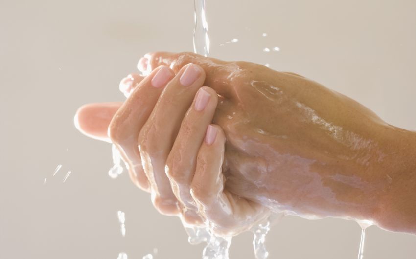 Das Bild zeigt zwei Hände unter dem Wasserhahn.