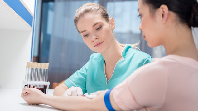 Eine Ärztin nimmt einer jungen Frau Blut ab
