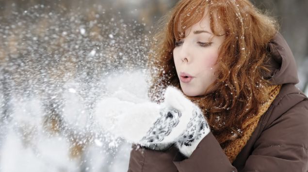 Das Bild zeigt eine Frau, die Schnee aus ihren Händen pustet.