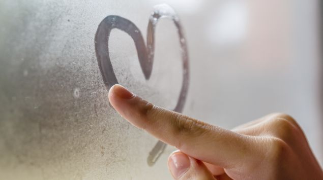 Jemand malt mit dem Finger ein Herz auf eine beschlagene Fensterscheibe.
