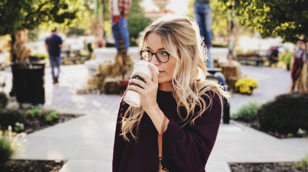 Frau trinkt Kaffee aus einem Starbucks Becher.