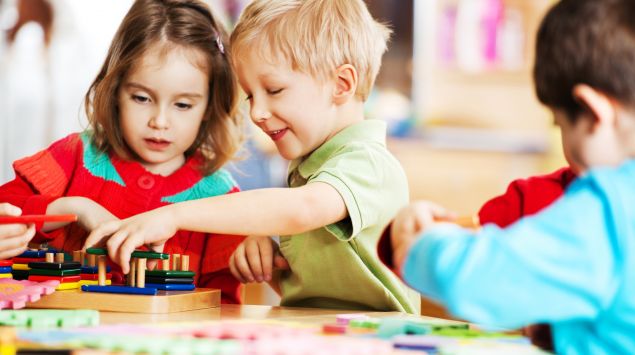 Drei Kinder spielen im Kindergarten an einem Tisch.