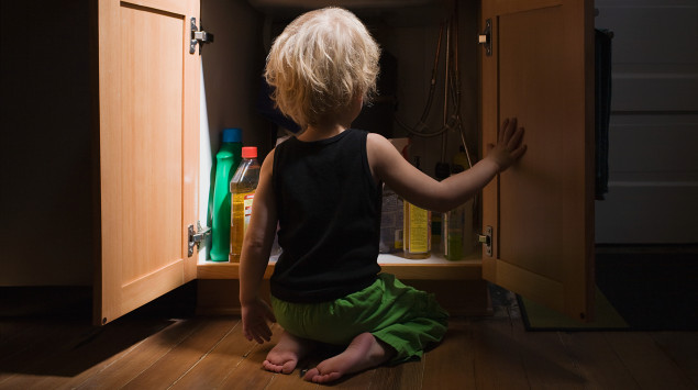 Ein Kind schaut in einen Schrank voller Putzmittel