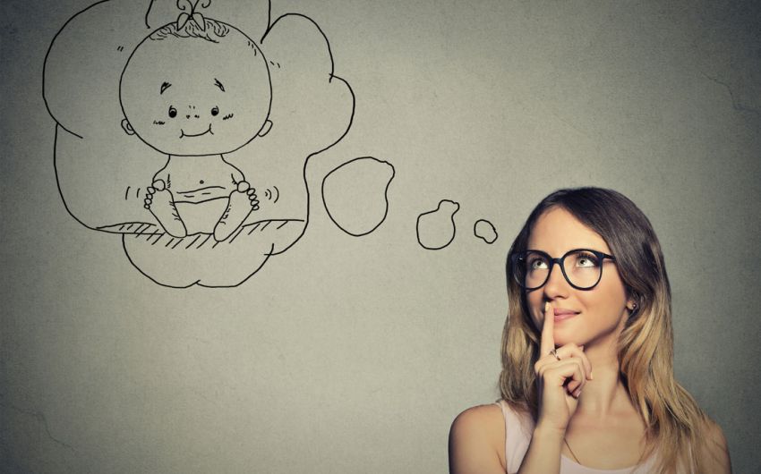 Eine junge Frau denkt darüber nach, ein Baby zu haben (symbolisiert durch eine Denkblase).