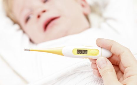 Ein schlagendes Kleinkind im Hintergrund, im Vordergrund ein Fieberthermometer mit dem Wert 39 Grad Celsius