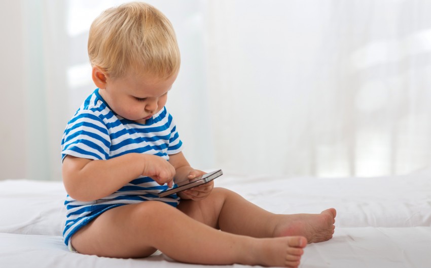 Ein Kleinkind betrachtet ein Smartphone.