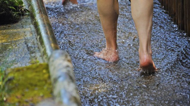 Jemand läuft für eine Kneipp-Kur durch ein Wasserpfad.