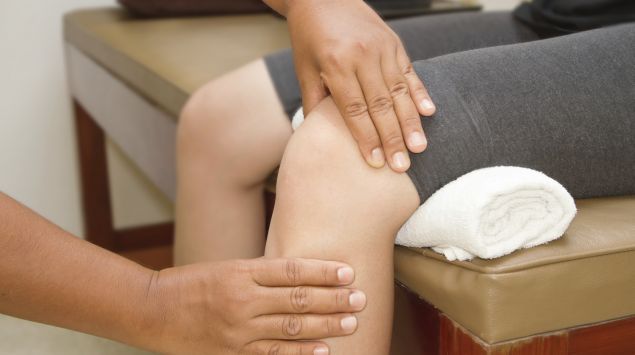 Ein Arzt untersucht das Knie eines Patienten.