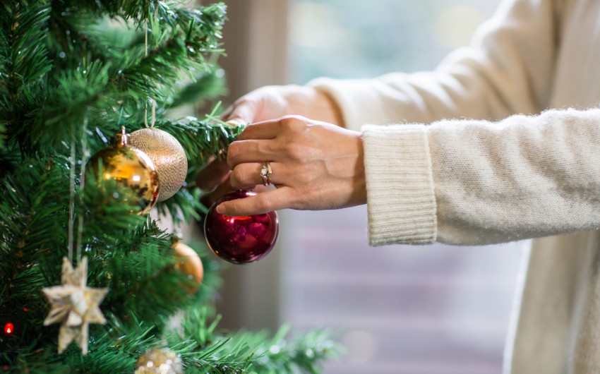 Eine Frau schmückt einen künstlichen Weihnachtsbaum.
