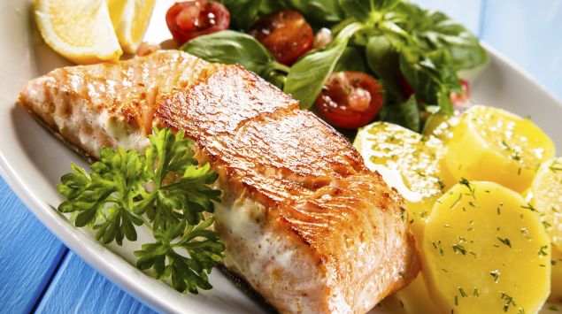 Man sieht einen Teller mit Lachfilet und Gemüse.