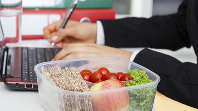 Man sieht eine Lunchbox mit Knäckebrot, Salat, Tomaten und Apfel.