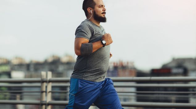 Ein leicht übergewichtiger Mann joggt über eine Brücke.