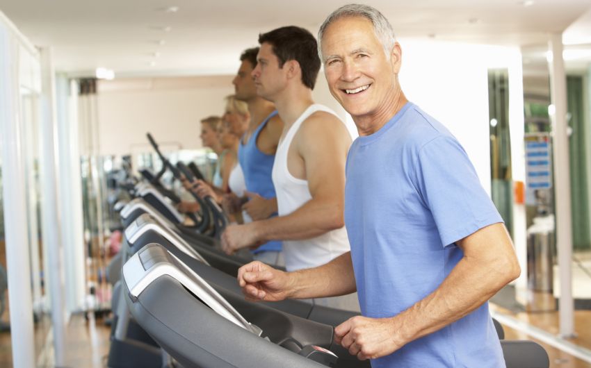 Ein älterer Mann neben anderen Männern auf dem Laufband.