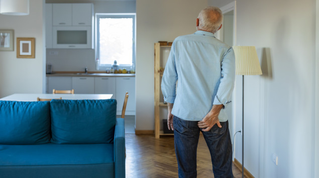 Rückansicht eines Seniors, der sich an das Gesäß fasst: In bestimmten Fällen ist bei vergrößerten Hämorrhoiden eine OP nötig.