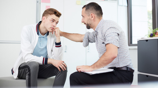 Ein Mann tröstet einen Jungen im Teenageralter: Psychische Erkrankungen kommen bei Kindern und Jugendlichen häufig vor.