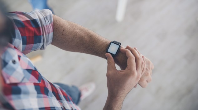 Ein Mann fummelt an seiner Smartwatch rum.