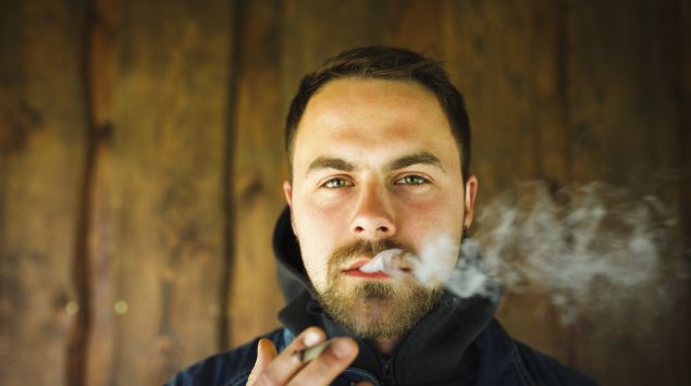 Das Bild zeigt einen jungen Mann beim Rauchen.