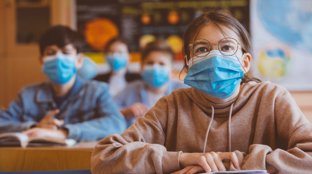 Schüler sitzen mit Maske im Unterricht. Sie soll verhindern, dass das Coronavirus sich dort verbreitet.