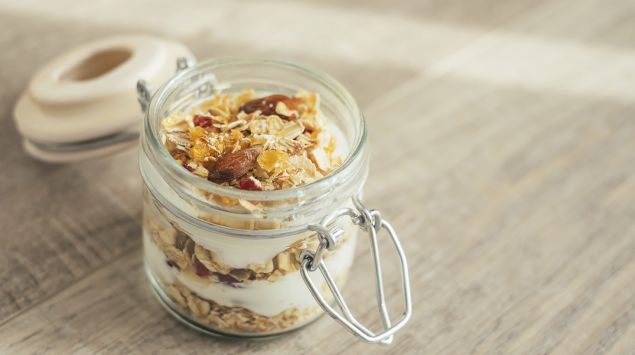 Man sieht ein Einweckglas mit Müsli und Joghurt.