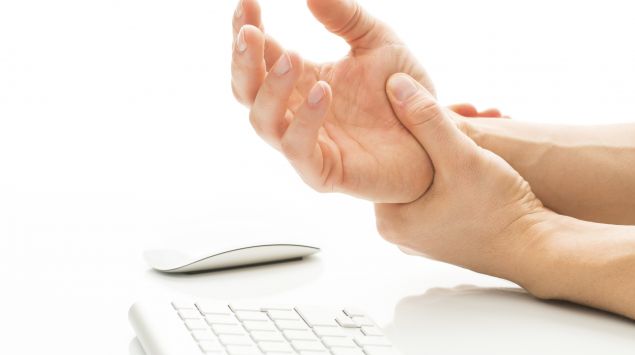 Das Bild zeigt eine Person, die sich ihre schmerzende Hand hält.