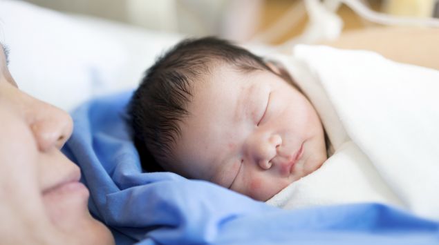 Man sieht eine Mutter mit ihrem Neugeborenen im Krankenhausbett.