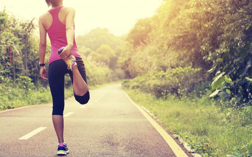 Eine Joggerin dehnt ihren Oberschenkel. Ein Aufwärmprogramm vor dem Sport ist wichtig, um einem Muskelfaserriss vorzubeugen.
