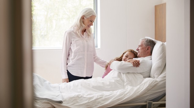 Enkelin umarmt ihren Großvater im Krankenhaus.