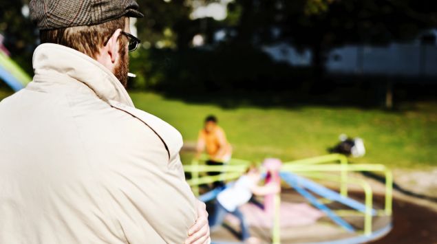 Ein Mann beobachtet Kinder auf dem Spielplatz.