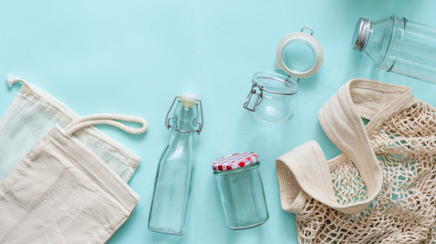 Zu sehen sind verschiedene wiederverwertbare Taschen, Beutel und Glasbehältnisse auf blauem Hintergrund.