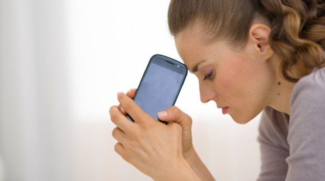 Eine Frau hält ratlos ihr Handy in den Händen.