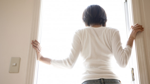 Eine Frau ist wegen des Coronavirus in Quarantäne. Sie schaut aus dem Fenster