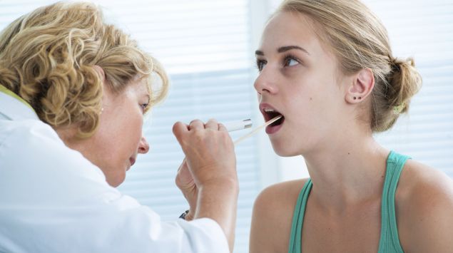 Das Bild zeigt eine Ärztin, die den Rachen einer Patientin untersucht.