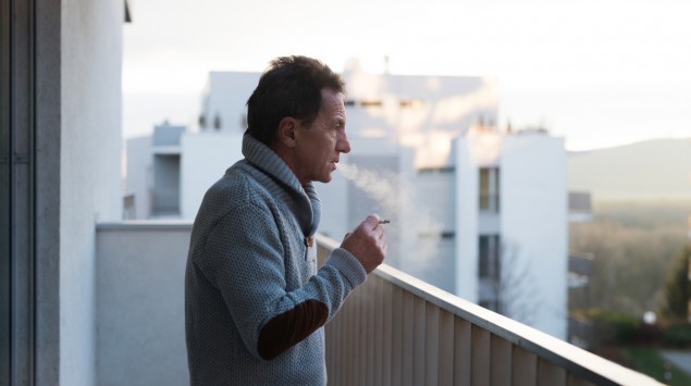 Ein älterer Mann raucht auf dem Balkon.