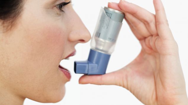 Das Bild zeigt eine Frau, die ein Asthmaspray benutzt.