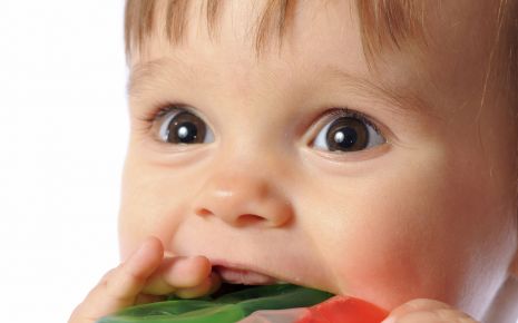 Ein Baby nimmt einen Beißring in den Mund.