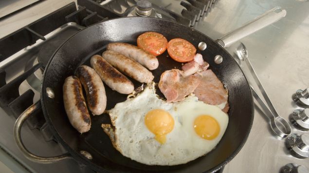 Das Bild zeigt Eier, Würstchen und Speck in einer Pfanne.