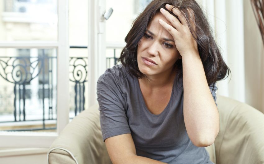 Eine Frau hält sich die Hand an den Kopf: Typische Symptome einer Gehirnerschütterung sind etwa Kopfschmerzen, Übelkeit und Schwindel.