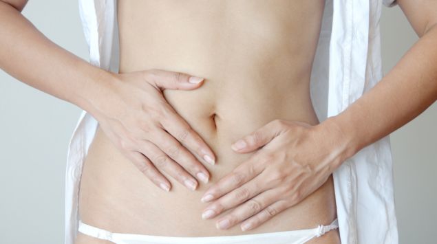 Eine halbnackte Frau hält ihren Bauch.