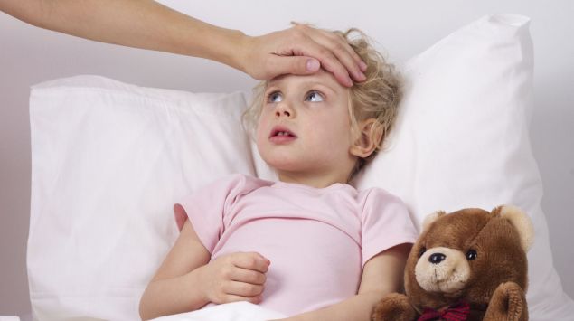 Das Bild zeigt ein Mädchen im Bett liegend, dem eine Hand auf die Stirn gelegt wird.