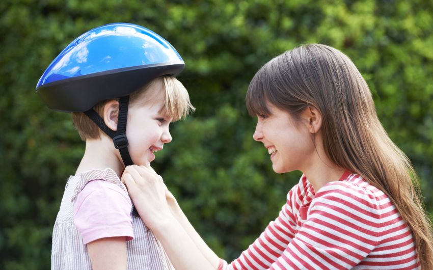 Eine junge Mutter setzt ihrem Sohn einen Fahrradhelm auf.