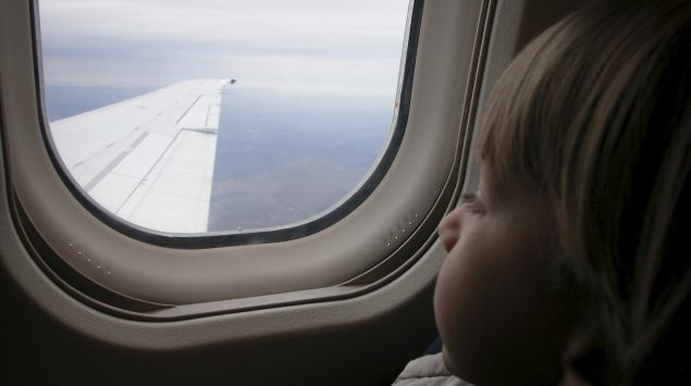 Kleiner Junge schaut aus dem Fenster eines Flugzeugs.