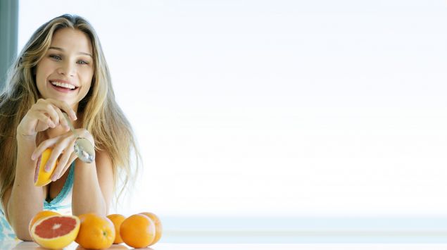 Eine junge Frau isst eine Grapefruit.
