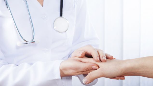 Das Bild zeigt eine Ärztin, die die Hand einer Patientin hält.
