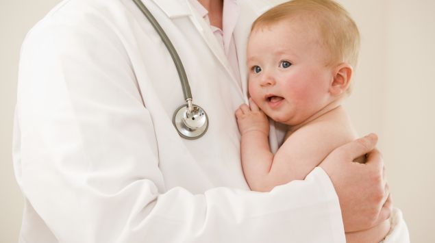 Das Bild zeigt ein Baby auf dem Arm eines Arztes.